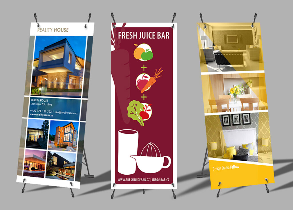 Tři reklamní roll-up bannery na stojanech: Reality House, Fresh Juice Bar a Design Studio Yellow